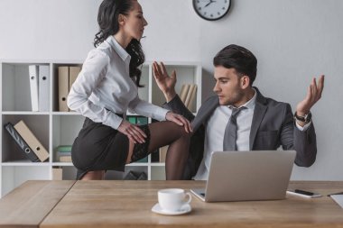 Seksi sekreter masada oturuyor ve neredeyse şok olmuş iş adamını gösteriyor.