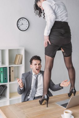 Kızgın iş adamı yüksek topuklu ayakkabılarla masanın üstünde duran seksi sekretere bakarken çığlık atıyor.