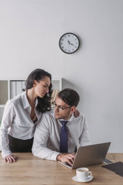 Ofiste onu baştan çıkarırken iş arkadaşının omzuna dokunan baştan çıkarıcı bir iş kadını.