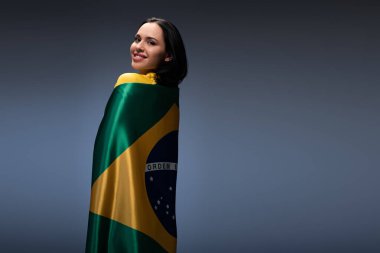 Brezilya bayraklarına sarılmış neşeli bayan futbol fanatiği.