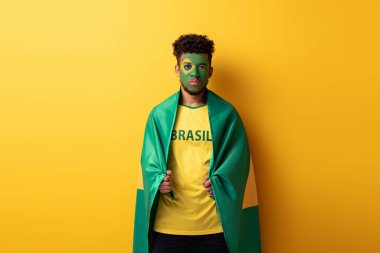 Brezilya bayraklarına sarıya sarılmış siyah yüzlü gerçek bir Afro-Amerikan futbol fanatiği.