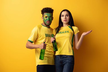 Erkek Afro-Amerikan futbol fanatiği boyalı suratlı ve kafası karışık kız elinde bira şişeleri tutuyordu. 