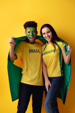 Yüzü boyalı yakışıklı Afro-Amerikan futbol fanatiği ve sarı bayraklı mutlu bir kız. 