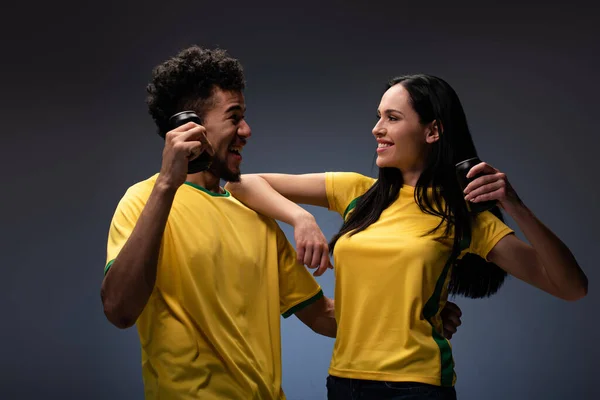 Alegre Pareja Multiétnica Aficionados Fútbol Camisetas Amarillas Sosteniendo Latas Con —  Fotos de Stock