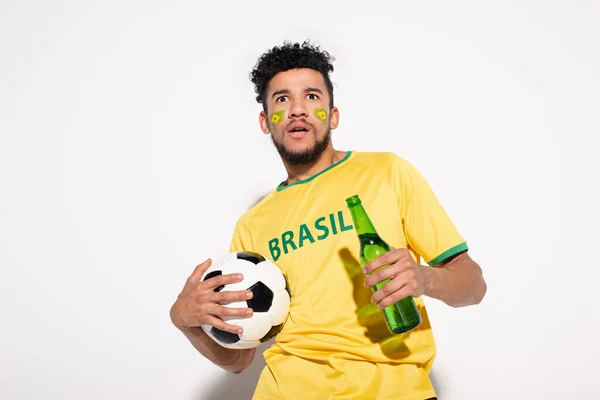 震惊的非洲美式足球迷拿着球和一瓶啤酒拿着灰色的 — 图库照片