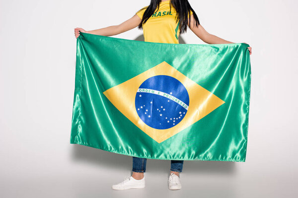обрезанный вид женского футбольного болельщика с бразильским флагом на сером
