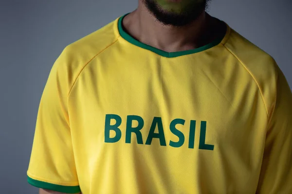 ブラジルのサインがグレーに孤立した黄色のTシャツのサッカーファンのクロップドビュー — ストック写真