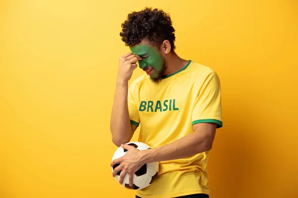 アフリカ系アメリカ人のサッカーファンを混乱させ顔をブラジルの国旗保持ボールとして黄色で描いた — ストック写真