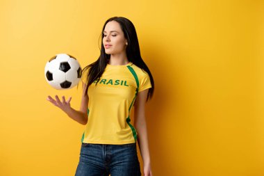 Çekici bayan futbol fanatiği sarı topun üstüne kusuyor.