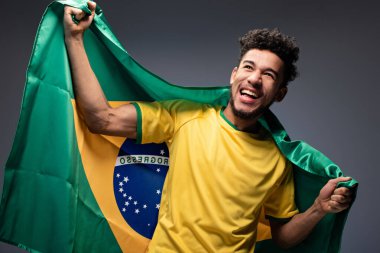 Mutlu Afro-Amerikan futbol fanatiği gri üzerinde Brezilya bayrağı tutuyor