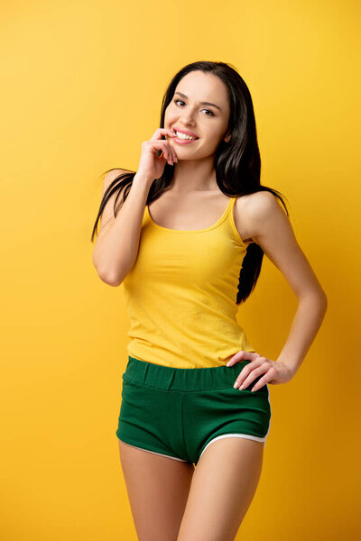 attractive cheerful girl in green shorts on yellow 