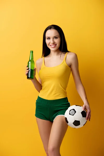 Uśmiechnięta Fanka Piłki Nożnej Trzymająca Piłkę Butelkę Piwa Żółto — Zdjęcie stockowe