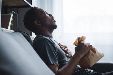 Evde panik atak geçirirken elinde kese kağıdı tutan Afro-Amerikan adam şok oldu.