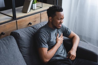 stressed african american man having heart attack at home clipart