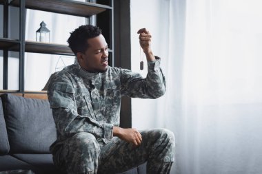 Stresli bir Afro-Amerikan askeri, evinde askerlik rozetine bakıyor. Travma sonrası stres bozukluğu yaşıyor.