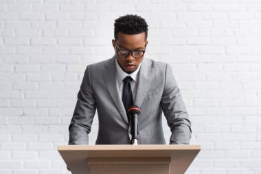 Konferans salonunda mikrofonlu Tribün 'de ciddi bir Afro-Amerikan iş konuşmacısı.
