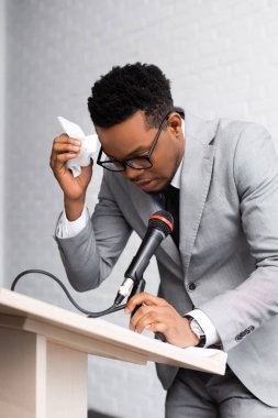 Ofisteki iş konferansında peçeteli ve mikrofonlu terli Afrikalı Amerikan konuşmacı.