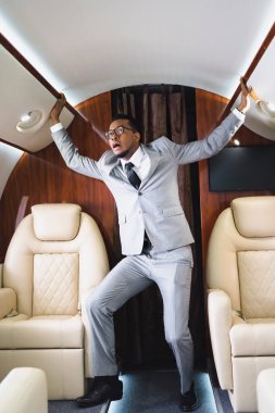 Korkmuş Afrikalı Amerikalı iş adamı özel uçakla uçarken panik atak geçiriyor.
