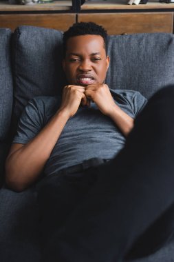 Evdeki koltukta oturan üzgün, Afrikalı Amerikalı adamın seçici odağı.