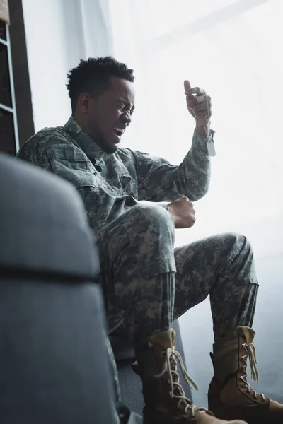 焦虑的美国士兵尖叫着并在家里拿着军徽 患有创伤后焦虑症 — 图库照片