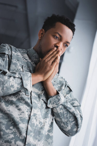 Worried african american soldier in military uniform at home