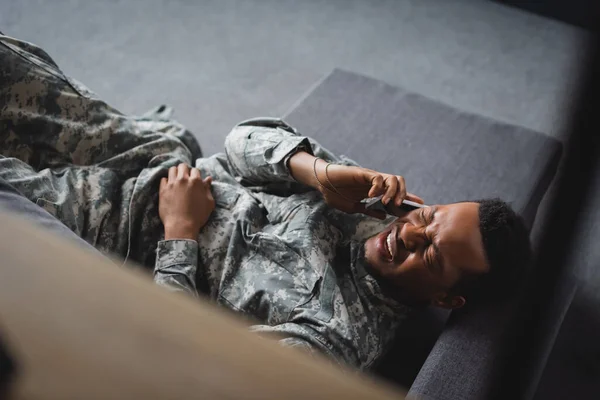 軍の制服を着たアフリカ系アメリカ人兵士が泣きながらスマートフォンで語り家でPtsdに苦しんでいるのを強調しました — ストック写真