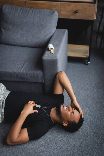 подчеркнул африканский американский солдат с армейским значком, имеющий сердечный приступ дома с таблетками, страдающих от ПТСР
  