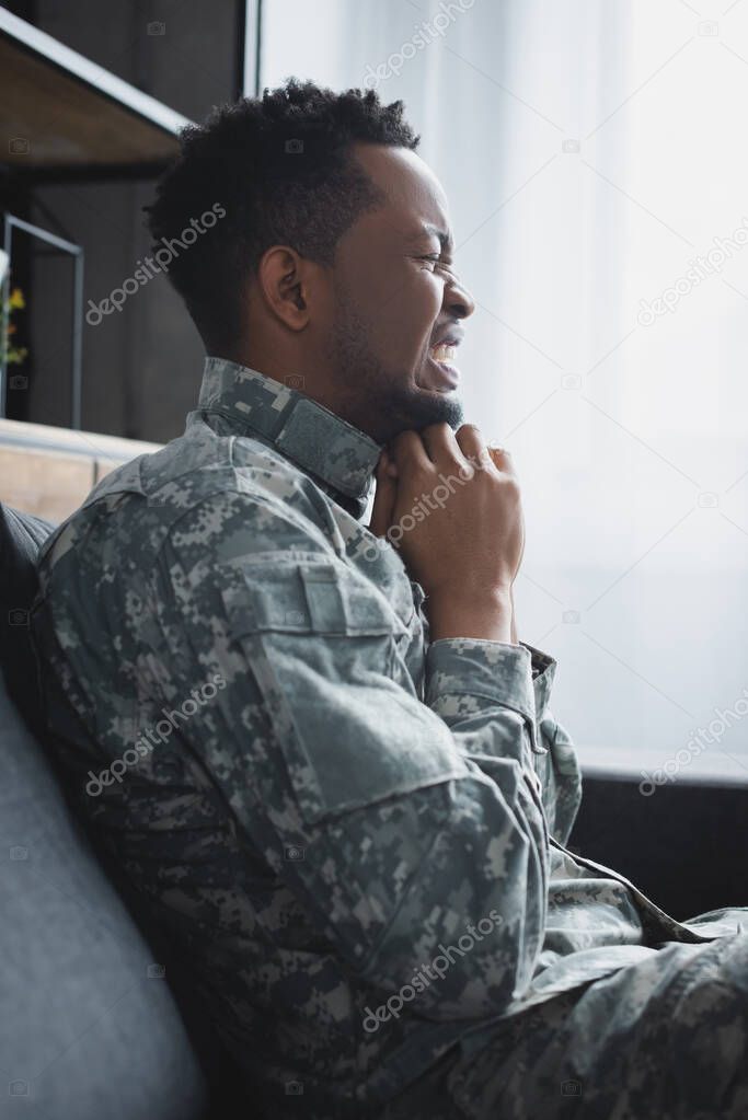 stressed african american soldier in military uniform suffering from PTSD at home