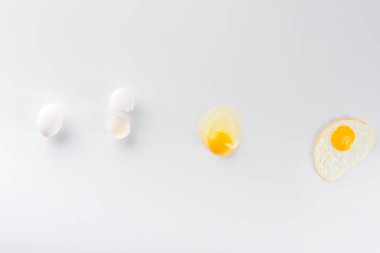 top view of eggs transformation from raw to fried on white  clipart