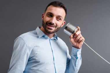 Teneke kutu tutan mutlu sakallı adam gri alanda izole edilmiş. 