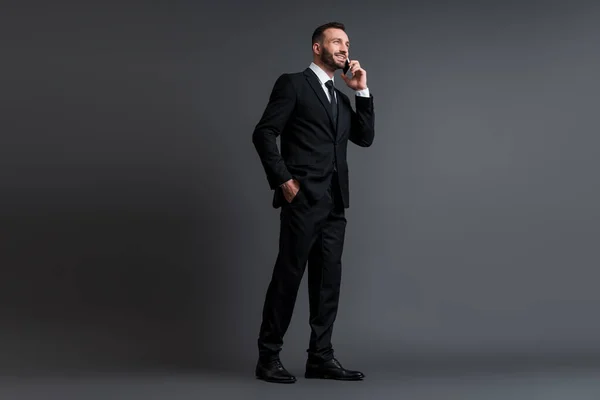 Šťastný Obchodník Obleku Mluvit Smartphone Zatímco Stojí Rukou Kapse Šedé — Stock fotografie