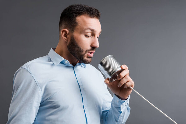 bearded man taking while holding tin can isolated on grey 