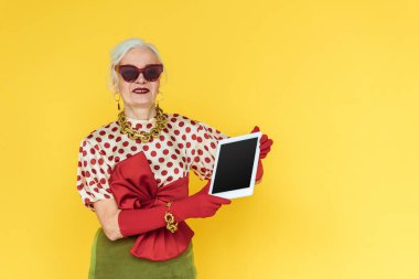 Sarı tablet tutarken gülümseyen son sınıf öğrencisi.