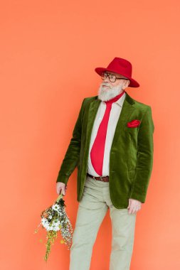 Tarz sahibi beyefendi mercanlarda izole edilmiş kır çiçekleri tutuyor. 