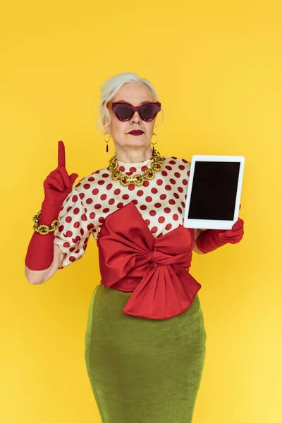 Wanita Senior Berpakaian Berkacamata Hitam Memegang Tablet Digital Dan Menunjuk — Stok Foto