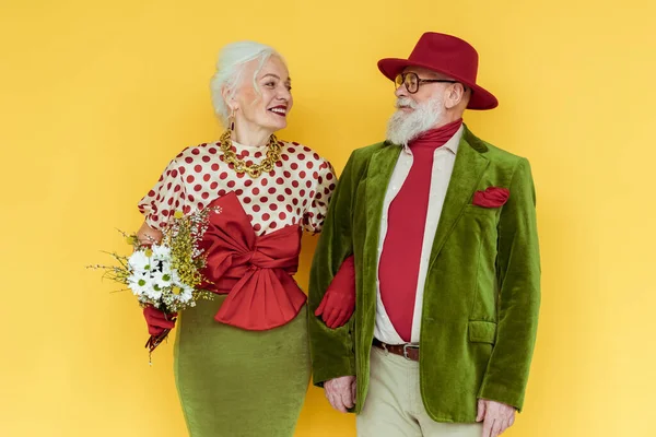 Stylish Senior Couple Bouquet Wildflowers Smiling Each Other Yellow Background — Stock Photo, Image