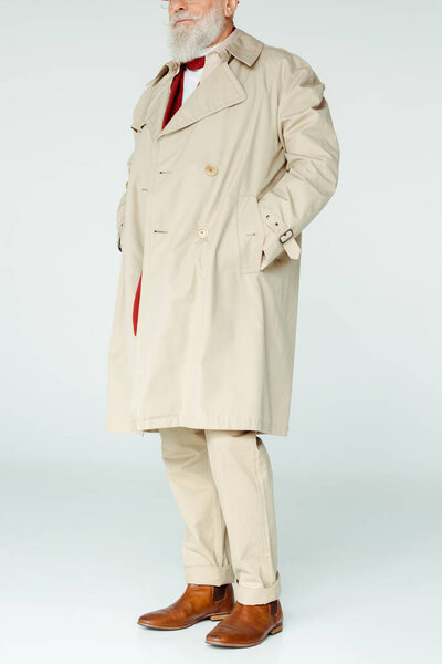Cropped view of stylish senior man in trench coat on white background