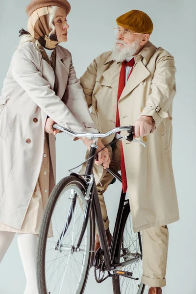 ハンサムなシニア男見ますで女でトレンチコート近く自転車絶縁上のグレー — ストック写真