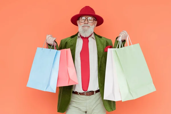 Stylish Senior Man Holding Shopping Bags Looking Camera Isolated Coral — Stock Photo, Image