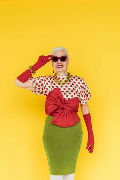 Stylish Senior Woman Smiling Holding Sunglasses Isolated Yellow — Stock Photo, Image