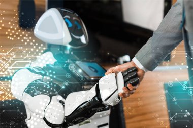 Ofiste gülümseyen robotla tokalaşan iş adamı görüntüsü