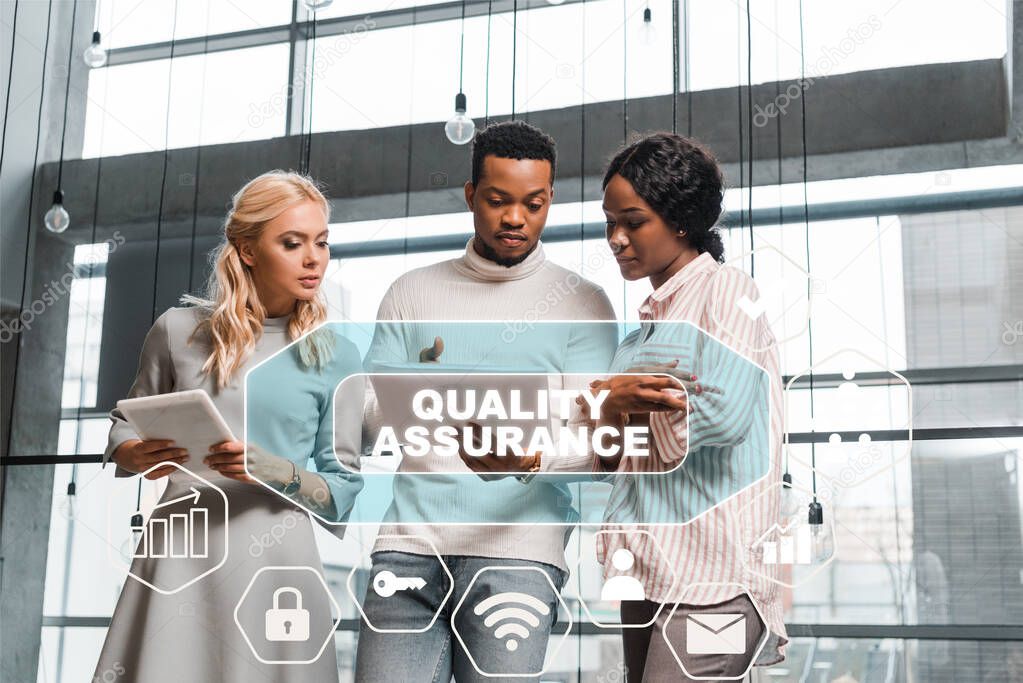 young businesswoman holding digital tablet while standing near african american colleagues looking at documents, quality assurance illustration