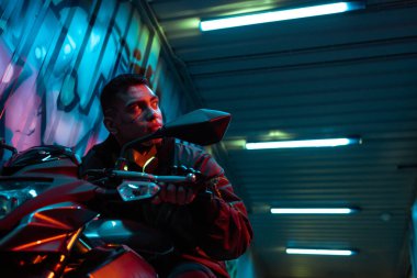 Motorsikletli karışık ırk siber punk oyuncusunun düşük açılı görüntüsü 