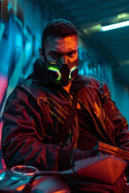 Koruyucu maskeli silahlı karışık ırk siber punk oyuncusunun seçici odağı