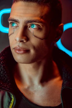 Yakışıklı ve çift ırklı siber punk oyuncusu Neon ışıklarının yakınından bakıyor. 