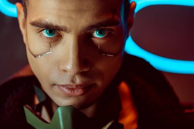 handsome and bi-racial cyberpunk player looking at camera near neon lighting  clipart