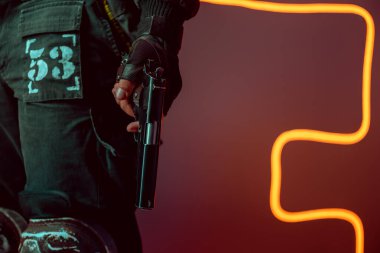 Siyah üzerine silahlı tehlikeli bir siber punk oyuncusunun neon ışıklı görüntüsü. 