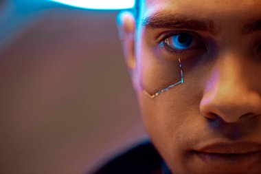 Yüzünde metalik plakalar ve kameraya bakan mavi gözlü karışık ırk siber punk oyuncusunun kırpılmış görüntüsü