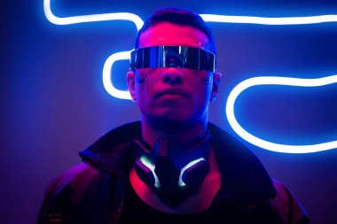Mavi neon ışıklı fütüristik gözlüklü karışık ırk siber punk oyuncusu 