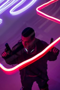 Silahlı, çift ırklı siber punk oyuncusunun Neon ışıklandırmasının yanında silah taşıdığı görülüyor. 